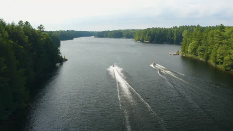 Jetskis-and-boats-towing-tubes-drive-alongside-each-other-on-a-river