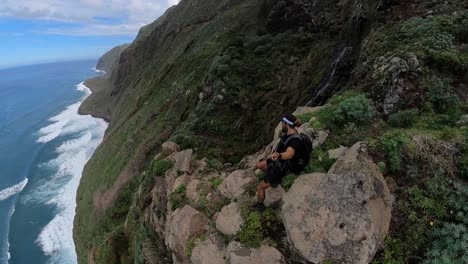 A-young-and-strong-man-is-hiking-down-the-edge-of-Quebrada-do-Negro-in-Madeira