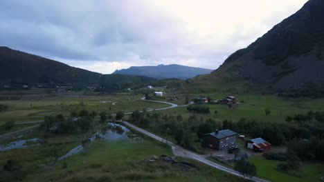 Volando-Hacia-Una-Casa-Blanca-De-Dos-Pisos-En-Un-Valle-De-Campo-Húmedo-En-Noruega