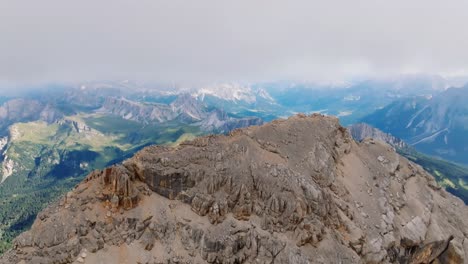 Luftaufnahme-Rückwärts-Mit-Felsigem-Berg-Und-Grünem-Tal-Im-Hintergrund-An-Bewölkten-Tagen-In-Italien