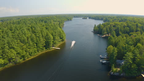 Drone-view-of-a-jet-ski-driving-away-down-a-river-away-from-camera-on-a-beautiful-summer-day