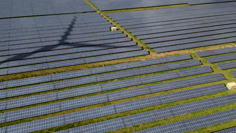 Aerial-view-of-solar-panels-with-shadow-of-a-spinning-wind-turbine