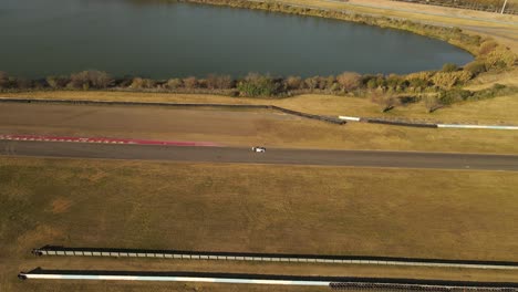 Aerial-view-following-white-car-on-racetrack-straight