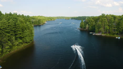Jet-ski-drives-down-a-beautiful-blue-river-surrounded-by-trees