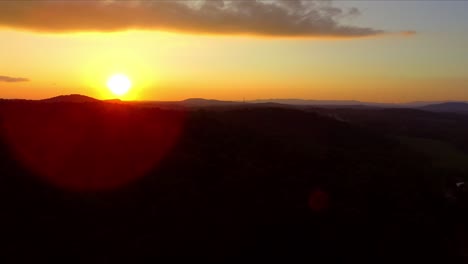 Sun-setting-beyond-silhouette-of-mountainous-horizon,-pedestal-shot