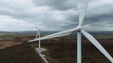 Close-up-drone-aerial-video-view-of-a-wind-farm-and-large-wind-turbines-turning-in-the-wind
