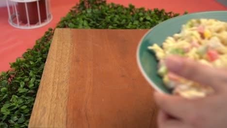 Placing-salad-pasta-over-wood-table-slow-motion
