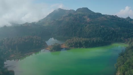 Aerial-flyover-natural-lake-and-forest-mountains-in-background-during-dense-foggy-day