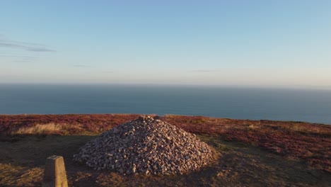 Sunrise-Stone-Cairn-Oben-Auf-Der-Küstenklippe-Mit-Luftdrohnen-Dolly,-Der-Mit-Der-Enthüllung-Des-Bristol-Channel-Sea-Bei-Holdstone-Down-North-Devon-UK-4k-Geschossen-Wurde