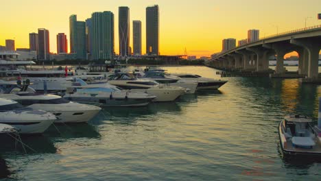 Aerial-video-of-yachts-at-a-miami-florida-marina-during-sunset,-smooth,-luxury-with-view-of-miami-skyline