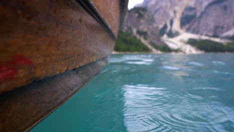 Close-up-creative-shot-of-the-outside-of-a-wooden-rowing-boat-gliding-through-the-water-of-a-blue-mountain-lake,-the-Lago-di-Braies-in-Italy