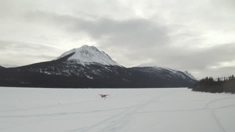 Aerial-shot-of-a-plane-taking-off-from-a-frozen-lake-in-winter