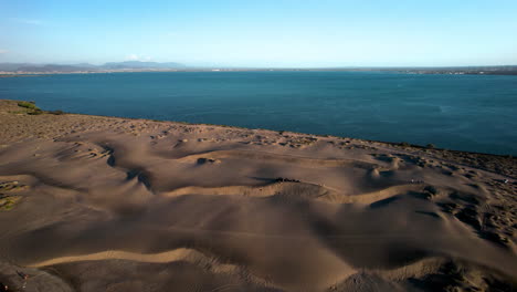 Downhill-drone-shot-of-athletes-practicing-sandboarding-in-La-Paz-Baja-California-Sur-Mexico