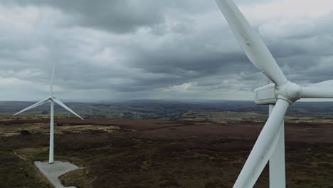 Close-fly-by-drone-aerial-video-view-of-a-wind-farm-and-wind-turbines-turning-in-the-wind