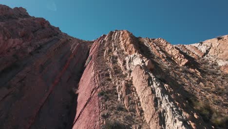 Planned-Shot-Of-Drone-Rising-Up-Close-To-High-Hill-Revealing-Stunning-Mountains-View,-North-Argentina