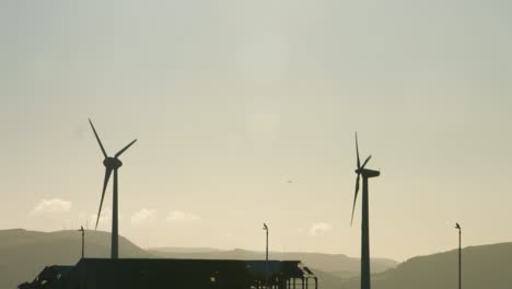 Windkraftanlagen-Drehen-Sich-Mit-Unglaublicher-Sonnenaufgangsbeleuchtung-Und-Dunstigem-Hintergrund-4k