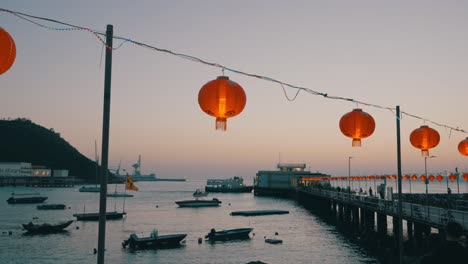 Shot-of-Chinese-lanterns-hang-above-the-dock-bridge-of-a-small-fisher-village-during-sunset