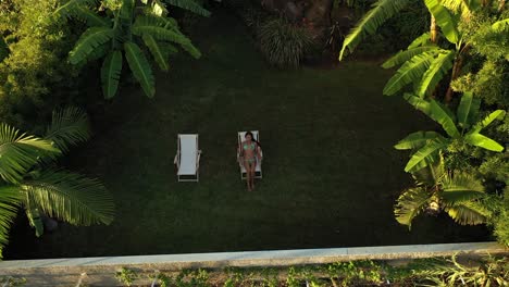 A-drone-shot-of-a-young-and-beautiful-woman-sitting-or-laying-down-in-the-sunchair-in-a-bikini
