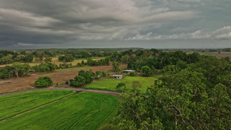 Guarumal-Panama-Aerial-v3-low-level-drone-flyover-cultivated-farmland-towards-the-skyline-with-car-driving-on-the-country-road-with-dark-stormy-clouds-in-the-sky---Shot-with-Mavic-3-Cine---April-2022