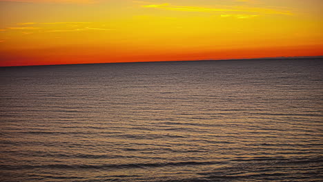 TIme-lapse-shot-of-golden-hour-with-orange-sky-at-horizon-behind-ocean