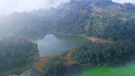 Cinematic-drone-flight-over-scenic-landscape-with-tropical-lake-and-clouds-on-mountaintop-in-Central-Java-at-summer
