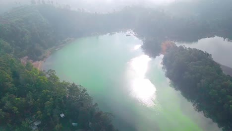 Aerial-shot-of-Telaga-Warna-with-the-reflection-of-the-morning-sun-in-Dieng-regency,-Wonosobo,-Central-Java,-Indonesia