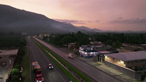 Drone-flyover-highway-with-traffic-in-Villa-Altagracia-during-pink-sunrise-on-Dominican-Republic