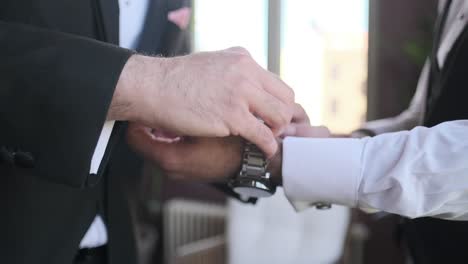 A-groom-dresses-and-someone-adjusts-his-watch,-preparing-for-a-wedding-1
