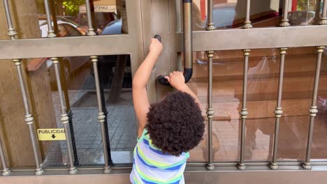 Entzückendes-Zweijähriges-Afrikanisch-europäisches-Kind,-Das-Seine-Mutter-Imitiert,-Versucht,-Die-Eingangstür-Mit-Den-Schlüsseln-Zu-öffnen