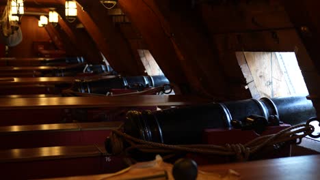 Close-up-of-metal-cannons-below-deck-of-a-wooden-old-warship
