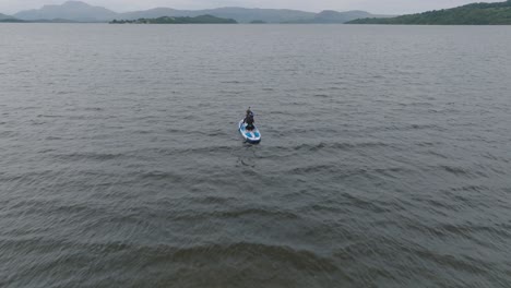 Tracking-Shot-Of-A-Young-Woman-Paddleboarding-On-Loch-Lomond