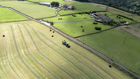 Green-Tractor-out-harvesting-hay-on-a-rural-landscape-aerial-view
