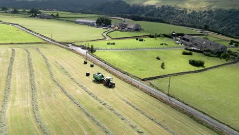 Green-Tractor-harvesting-hay-on-a-rural-Yorkshire-landscape-aerial-view