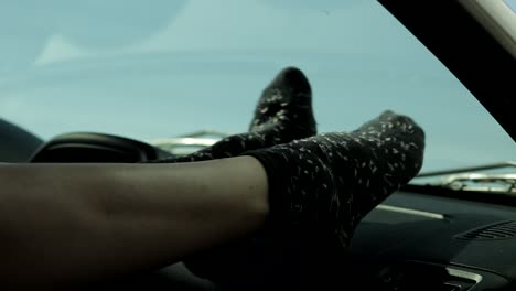 Close-up-of-woman's-feet-dancing-on-car-dashboard