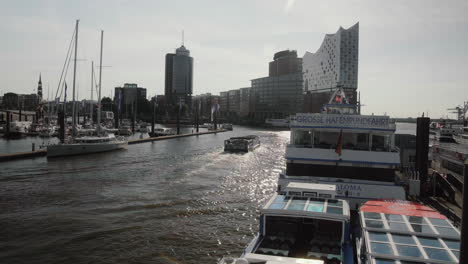 Tourist-Boat-Passing-By-At-Hamburg-Landungsbrücken-With-Elbphilharmonie-In-The-Background