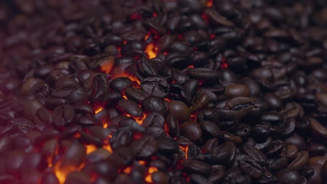 Zooming-in-close-up-shot-of-coffee-beans-roasting-on-a-orange-and-yellow-glowing-fire