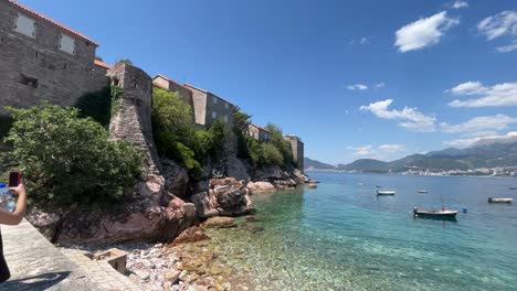 A-young-lady-taking-a-photo-of-the-beach-and-walls-of-the-famous-hotel-in-Montenegro-called-sveti-stefan