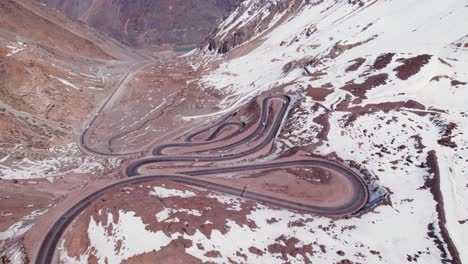 Vehicles-Driving-On-Dangerous-Hairpin-Road-On-Snowy-Mountains-Of-Los-Andes-In-Chile