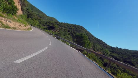 POV-shot-of-a-recreational-cyclist-enjoying-a-scenic-mountain-pass-descent-and-crossing-over-valley-bridge-on-a-country-road,-Catalunya,-Spain