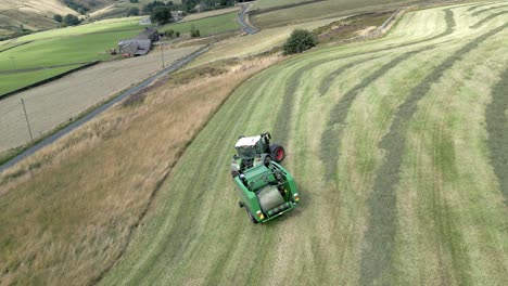 Aerial-footage-of-a-tractor-drives-across-field-and-makes-bales-from-cut-straw