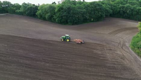 Aerial-tracking-shot-of-a-tractor-plowing-a-field-in-the-UK