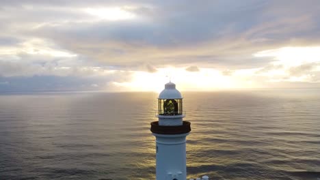 Drone-aerial-view-of-the-sunrise-behind-the-famous-lighthouse-of-Byron-Bay,-Australia