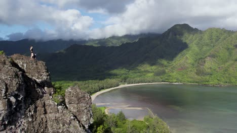 Hiker-Standing-On-Top-Of-Cliff-Of-Crouching-Lion-Trail-With-Kahana-Bay-Beach-Park-At-Summer-In-Oahu,-Hawaii