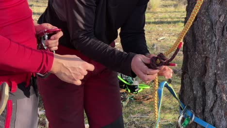 Man-and-woman-hands-close-up-tying-knots-at-Spanish-forest,-for-height-pruning-and-gardening