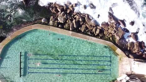 Drone-aerial-top-view-of-people-swimming-in-the-famous-Bronte´s-rockpool,-in-Australia