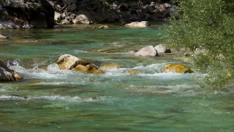 Mountain-river-water-splashing-on-cliffs-of-riverbed,-streaming-from-high-Alpine-peaks