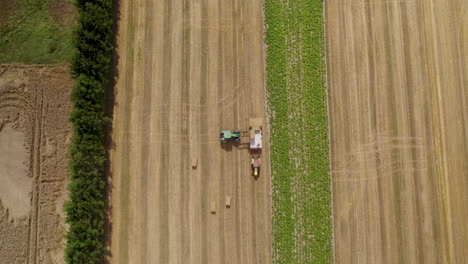 Hay-bale-harvesting-season,-hard-work-on-field-during-hot-day,-aerial-top-down-view