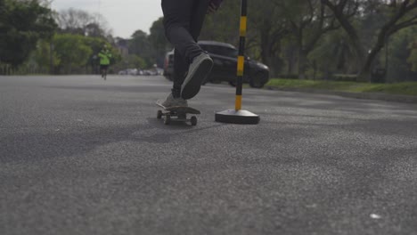 Man-rides-skateboard-between-cones-on-street,-follow-behind