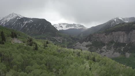 área-Forestal-En-Las-Montañas-Rocosas-Con-Picos-Nevados-Que-Conducen-A-Un-Cañón,-Colorado-Usa,-Tiro-Aéreo