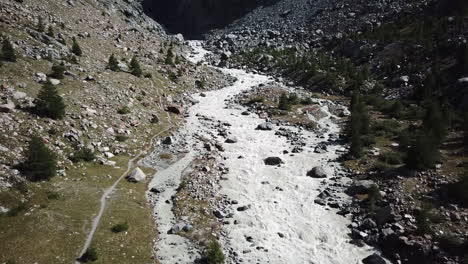 Drohne-Luftaufnahme-Eines-Bergflussbettes,-Wasser-Kommt-Aus-Der-Gletscherschmelze,-Schweizer-Alpenlandschaft,-Schlammiges-Wasser-Mit-Starker-Strömung